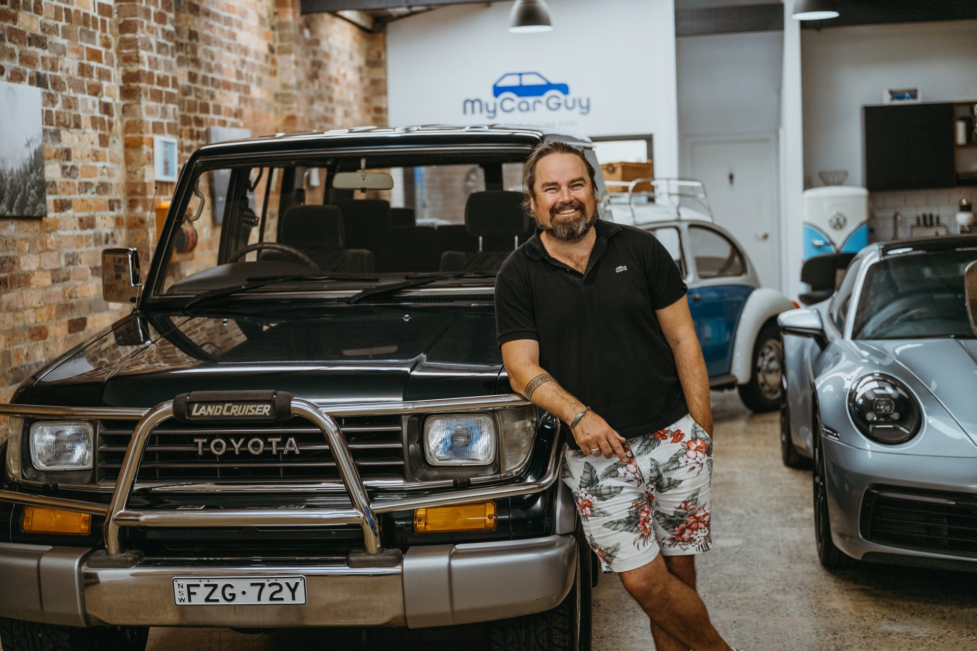 My Car Guy showroom featuring a Toyota Land Cruiser, Porsche 911, and VW Beetle